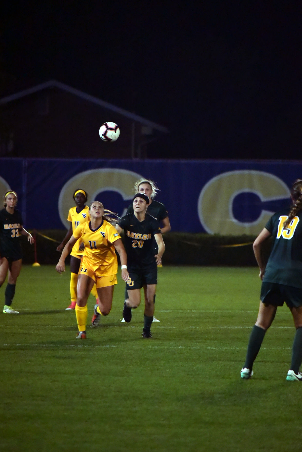 WVU midfielder Addison Clark eyes the ball as she competes with Baylor midfielder Julie James to get there.